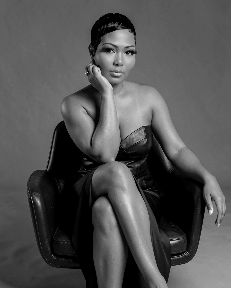 Woman sitting on a chair, resting her chin on her hand, wearing a strapless dress, in black and white.