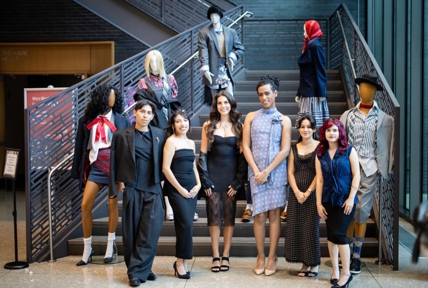Group of ten diverse people standing and sitting on a staircase in a modern building, posing for a photo.