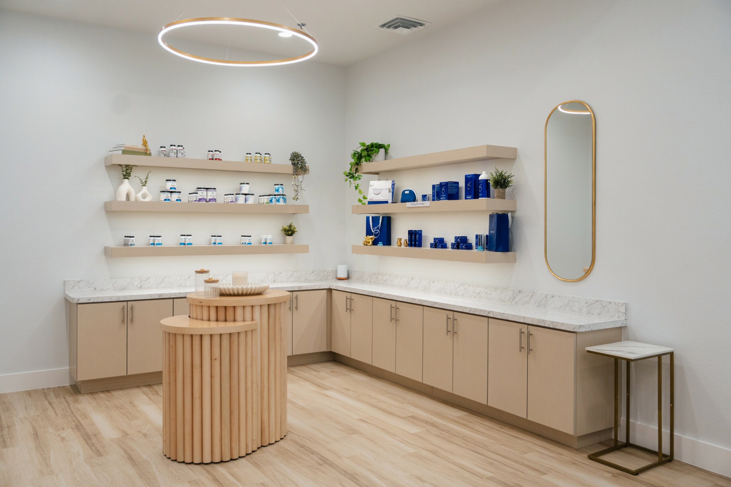 Clean, modern room with shelves, a mirror, and a wooden table, featuring light-colored walls and flooring.