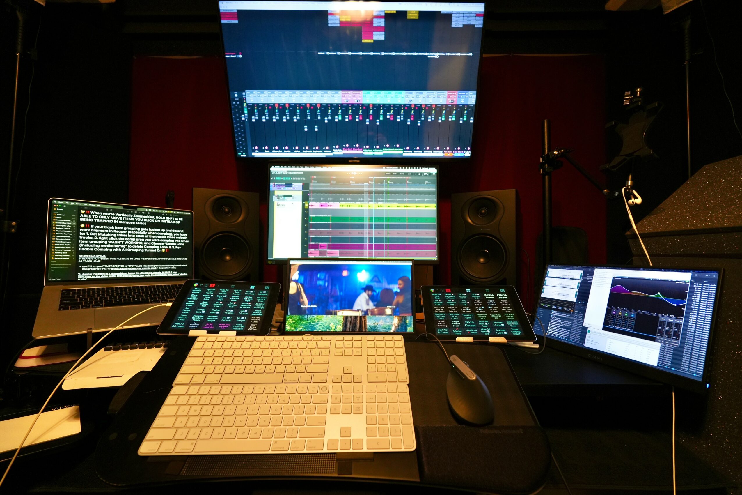 Music production setup with multiple screens, a keyboard, and audio equipment in a studio.