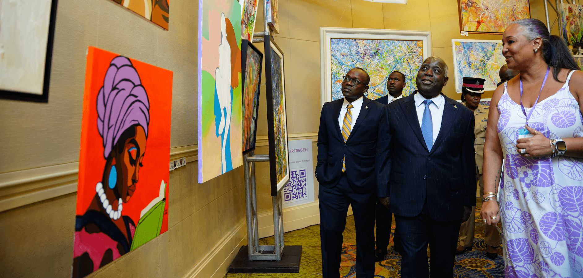 Group of four people viewing colorful artwork in an art gallery, with paintings on the wall behind them.